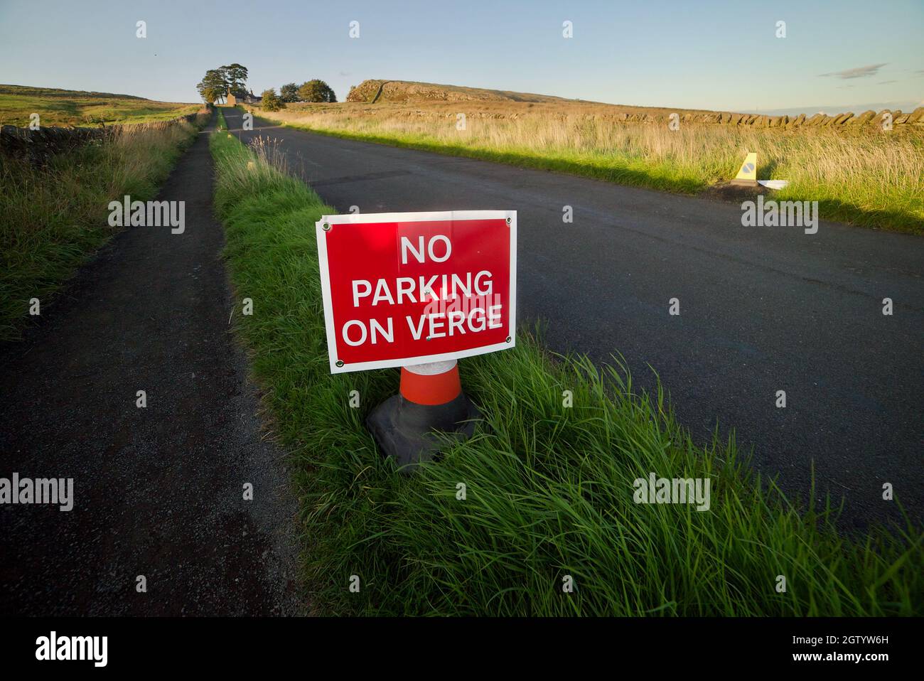 NO PARKING ON VERGE sign post along a small English country road. A temporary road sign asking drivers not to park on the road verge side. Stock Photo