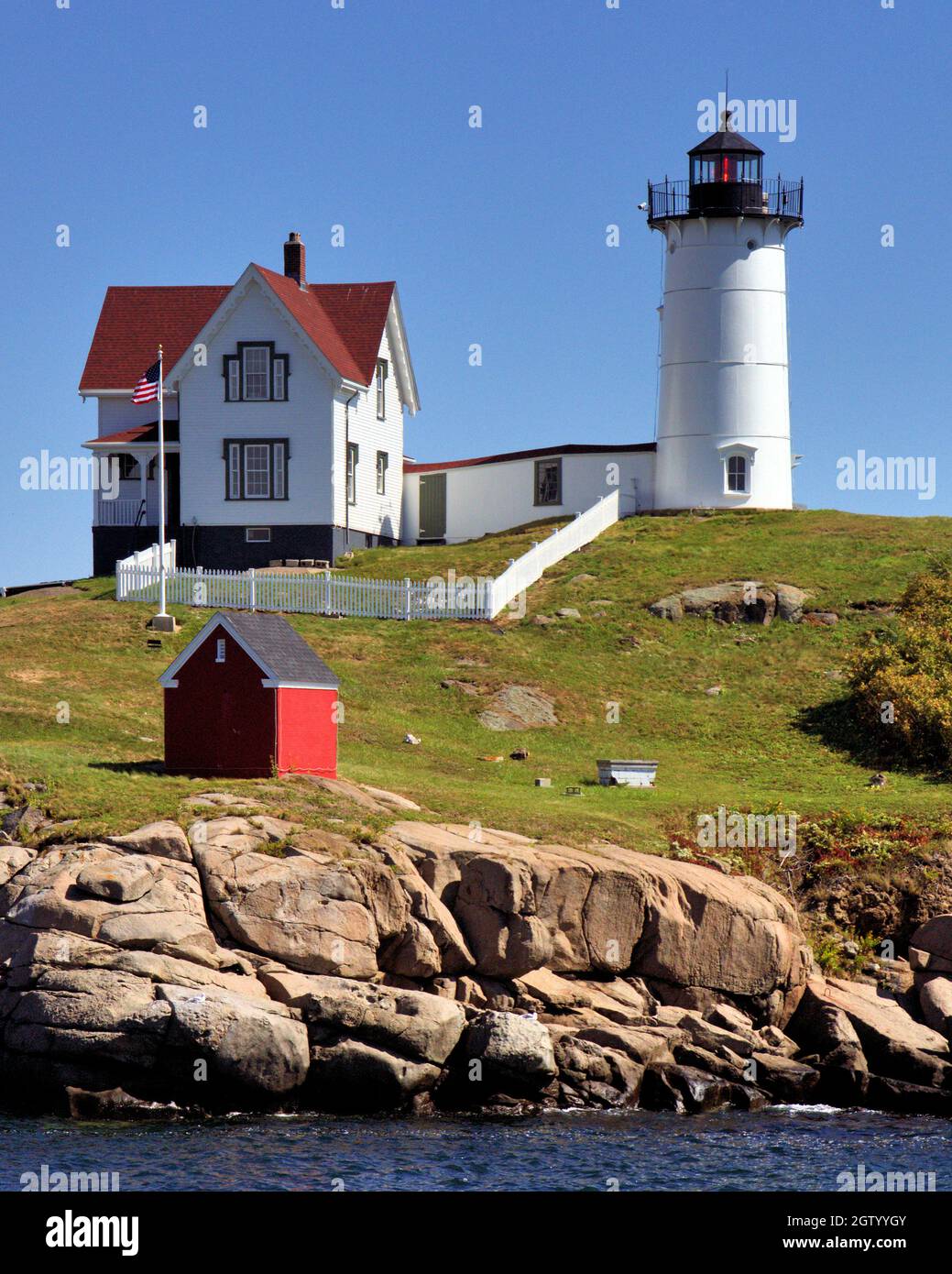 Lighthouse Amidst Rocks And Buildings Against Sky Stock Photo