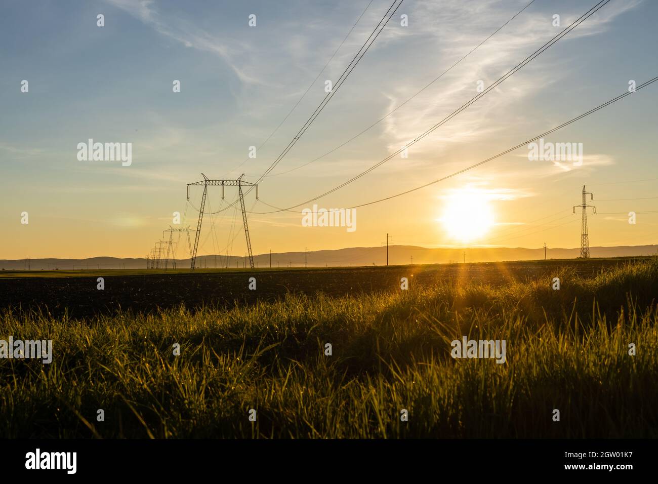 High voltage electric transmission towers and power lines at sunset. Stock Photo