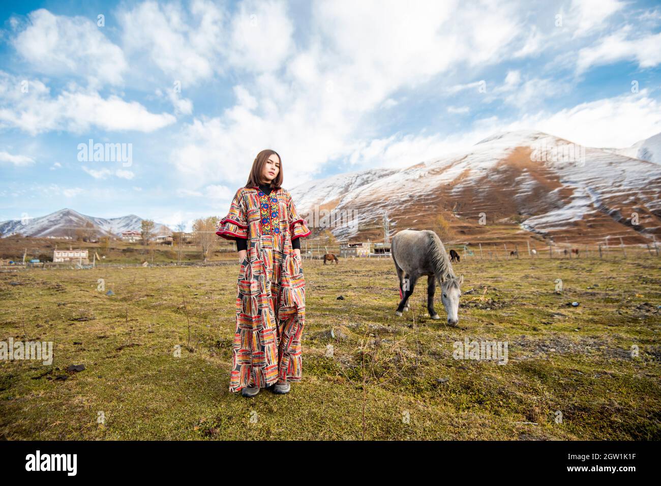 Portrait Of Woman Standing On Field Against Snowcapped Mountains Stock Photo