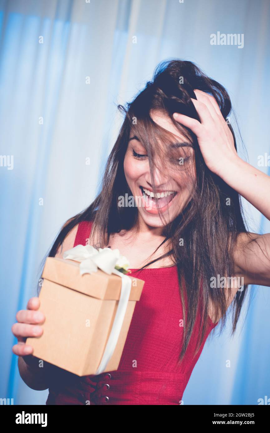 Cheerful Young Woman Holding Gift At Home Stock Photo