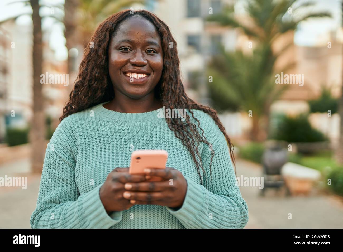 Young african woman smiling happy using smartphone at the city Stock ...