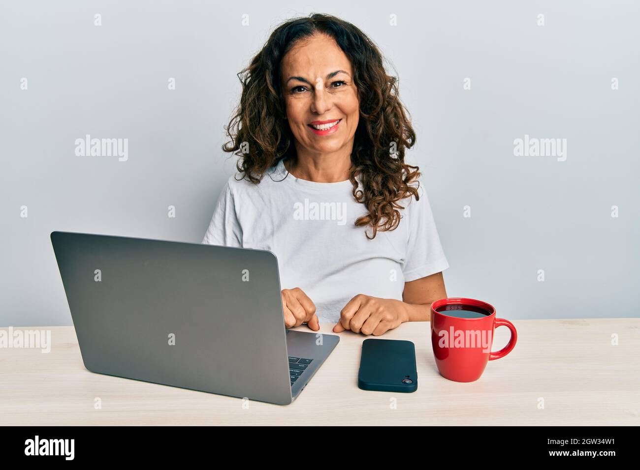 Beautiful middle age woman working at the office using computer laptop ...