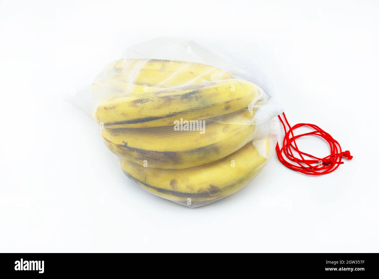 Ripe Bananas Packed In A White Reusable Mesh Bag With Red String, Isolated On A White Background