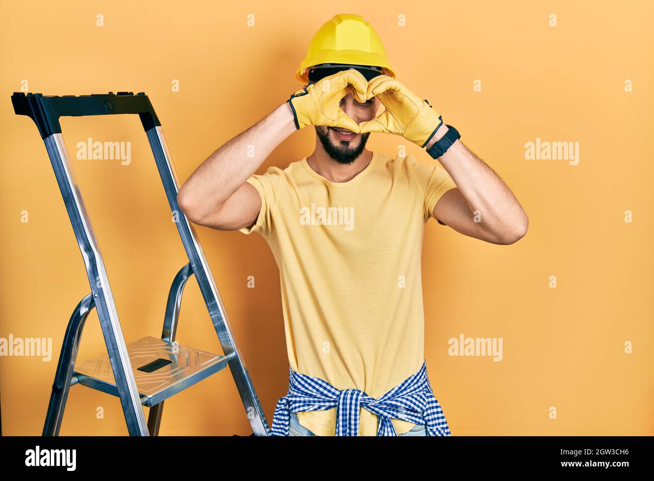 Handsome man with beard by construction stairs wearing hardhat doing