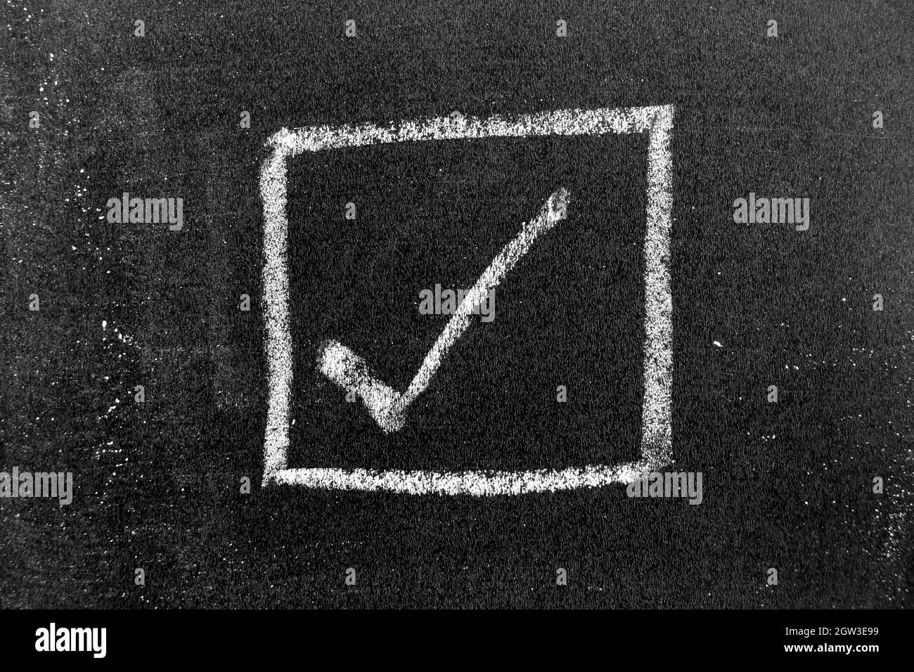 White color chalk hand drawing in right checkmark in square box shape on black board background