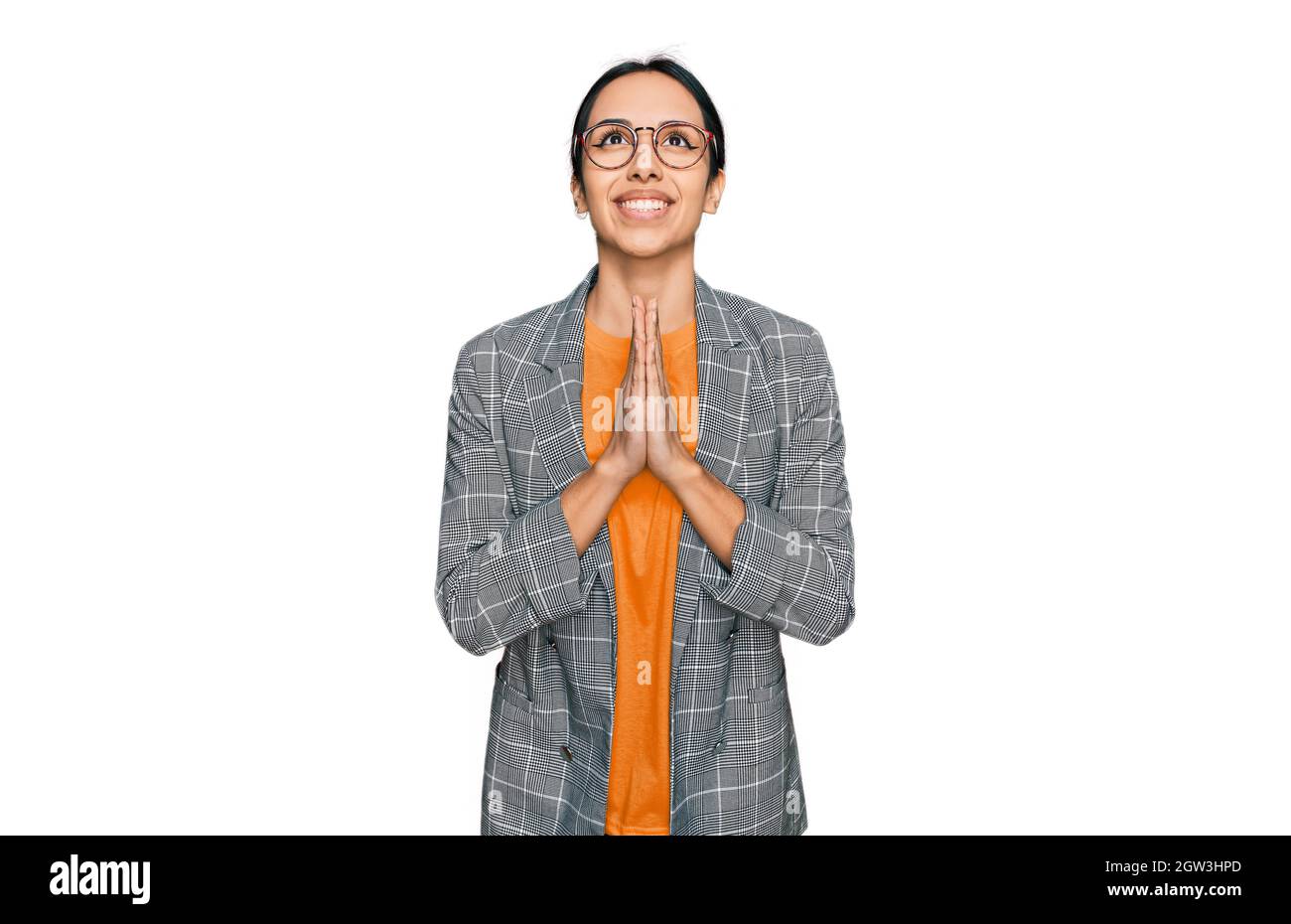 Young hispanic girl wearing business jacket and glasses begging and praying with hands together with hope expression on face very emotional and worrie Stock Photo