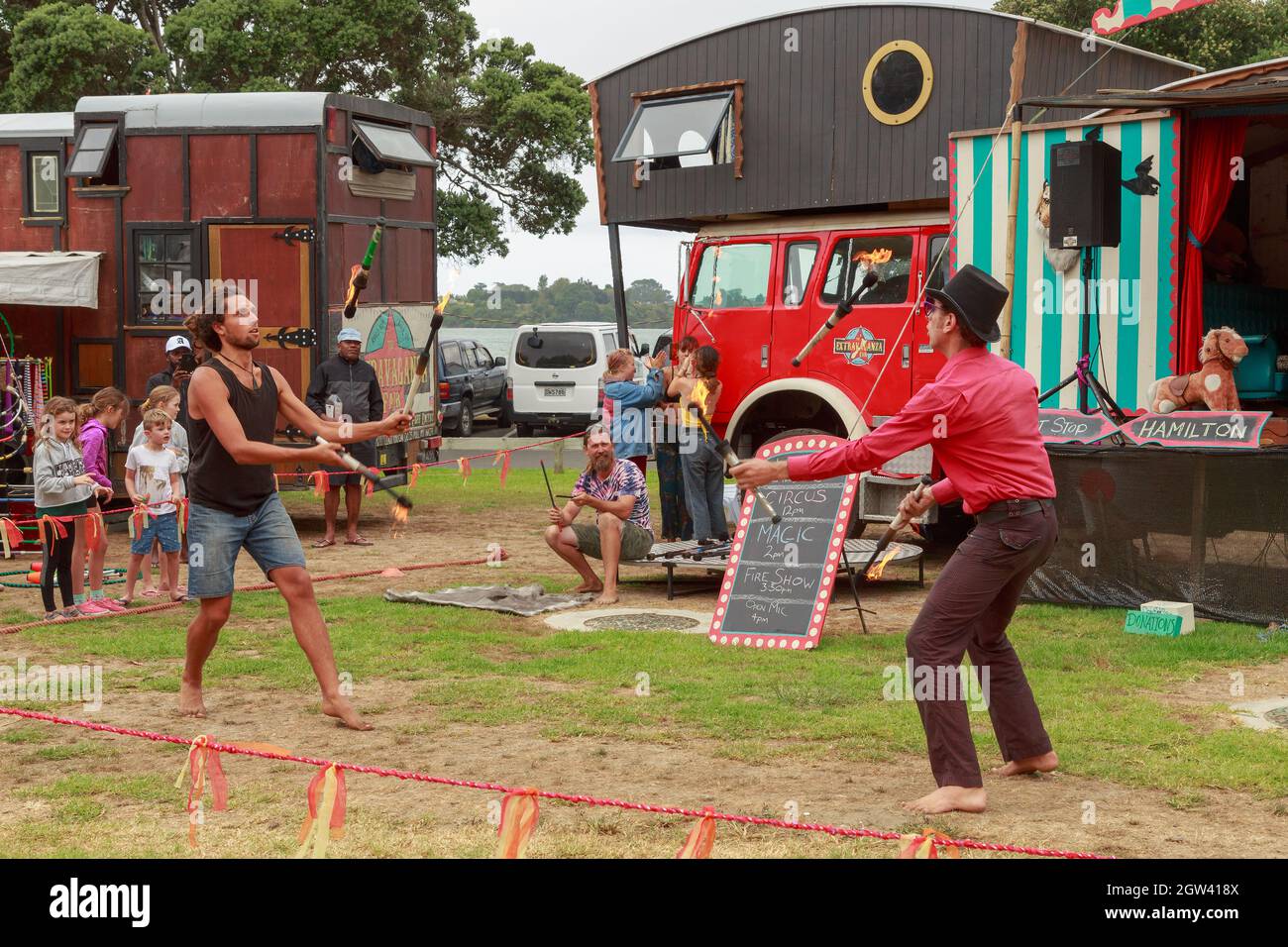 Jugglers tossing flaming batons to each other at a traveling fair. Tauranga, New Zealand Stock Photo
