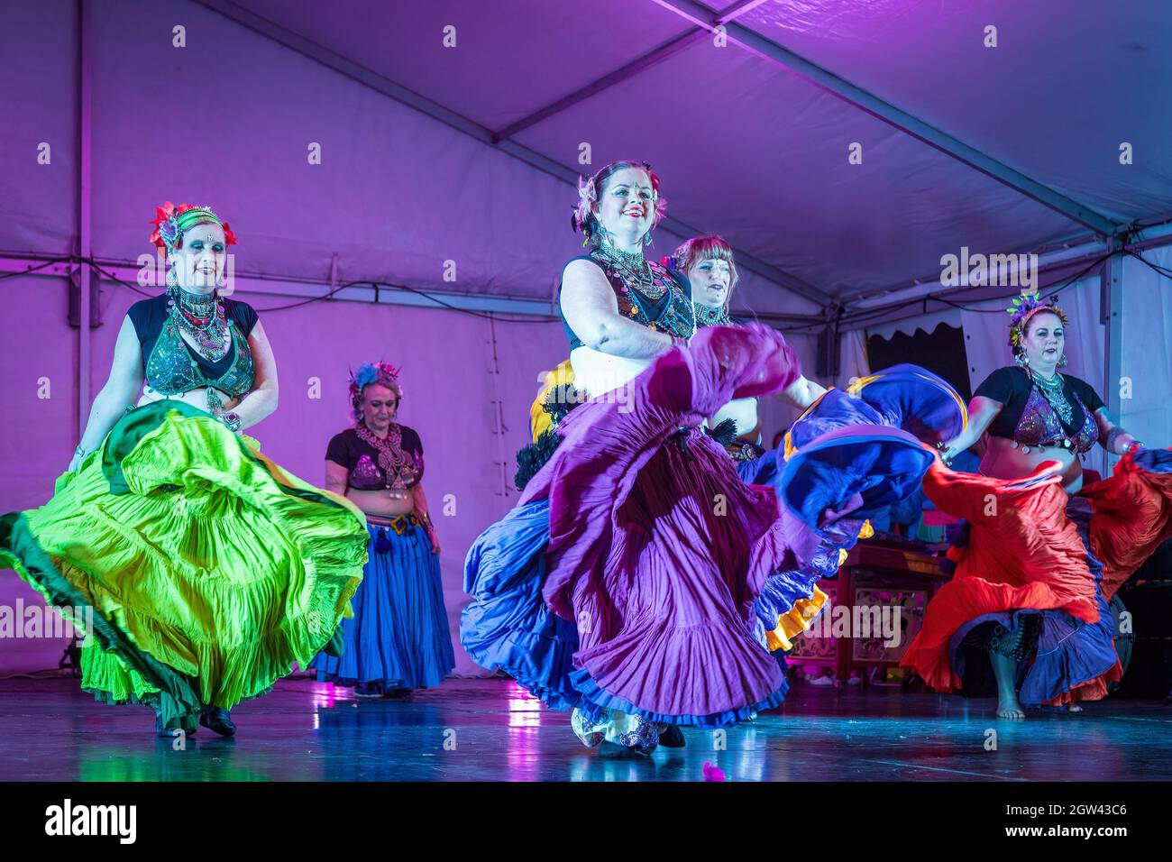 Belly dancers in gypsy costumes, their skirts flying as they perform on stage Stock Photo