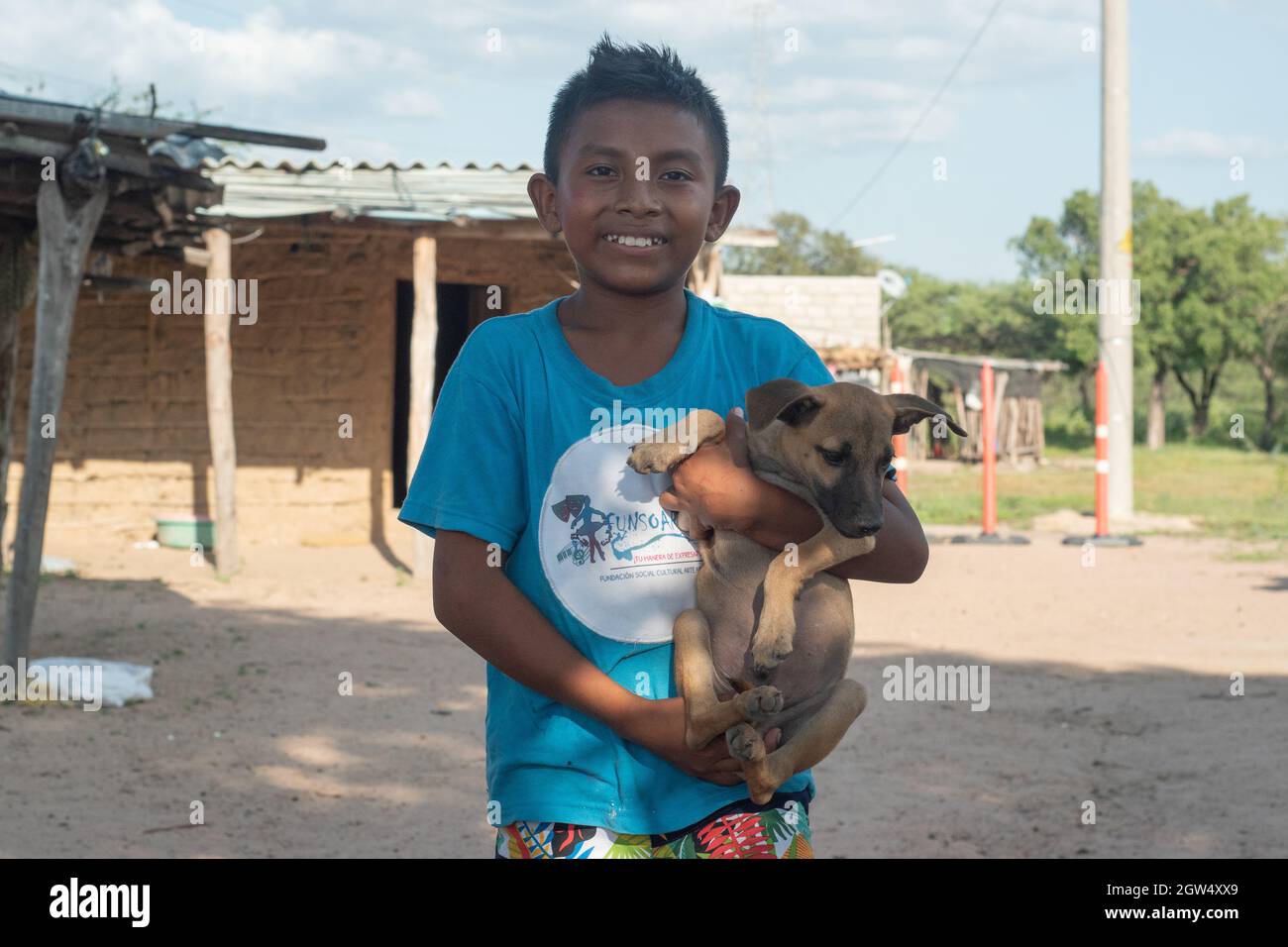 A Wayuu indigenous child poses for a photo with his dog during a Humanitarian Mission developed by 'De Corazon Guajira' in Mayapo at La Guajira - Colombia were they visited the Wayuu indigenous communities 'Pactalia, Poromana, Perrohuila' on September 26, 2021. The Guajira region in Colombia is the poorest region in Colombia, with its people commongly living without drinkable water, electricity and food. Stock Photo