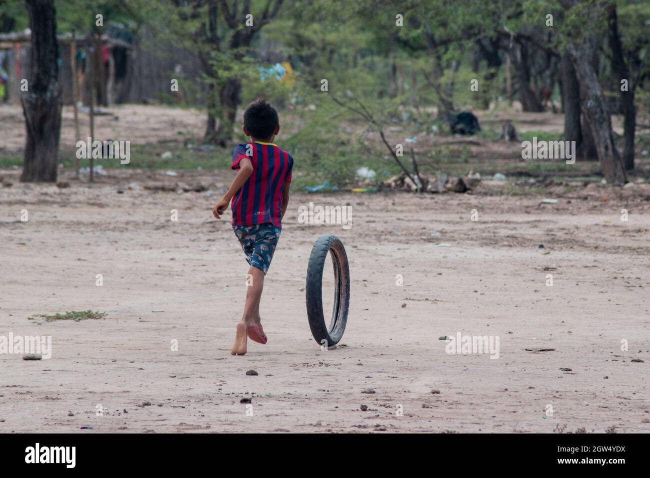 A Wayuu indigenous community child plays with a tire thrown to the garbage during a Humanitarian Mission developed by 'De Corazon Guajira' in Mayapo at La Guajira - Colombia were they visited the Wayuu indigenous communities 'Pactalia, Poromana, Perrohuila' on September 26, 2021. The Guajira region in Colombia is the poorest region in Colombia, with its people commongly living without drinkable water, electricity and food. Stock Photo