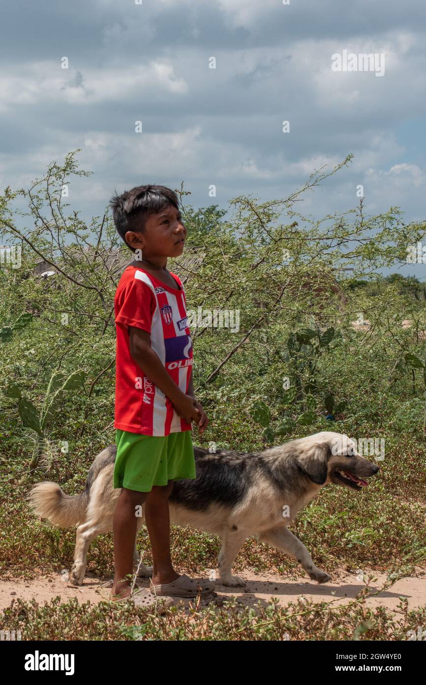 A Wayuu indigenous community child walks its dog during a Humanitarian Mission developed by 'De Corazon Guajira' in Mayapo at La Guajira - Colombia were they visited the Wayuu indigenous communities 'Pactalia, Poromana, Perrohuila' on September 26, 2021. The Guajira region in Colombia is the poorest region in Colombia, with its people commongly living without drinkable water, electricity and food. Stock Photo