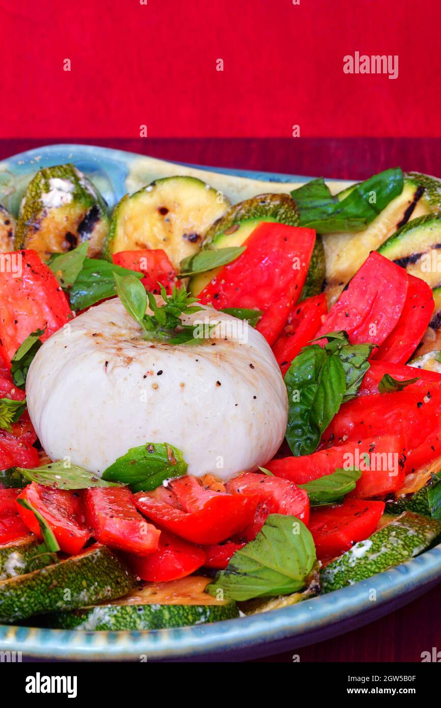 Dish of burrata cheese salad with fresh tomatoes and grilled zucchini
