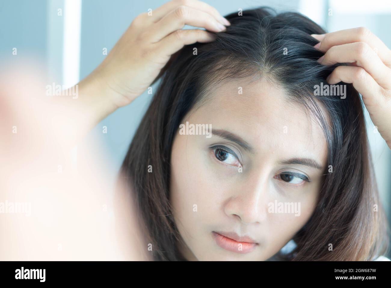 Reflection Of Woman Looking At Hair On Mirror Stock Photo