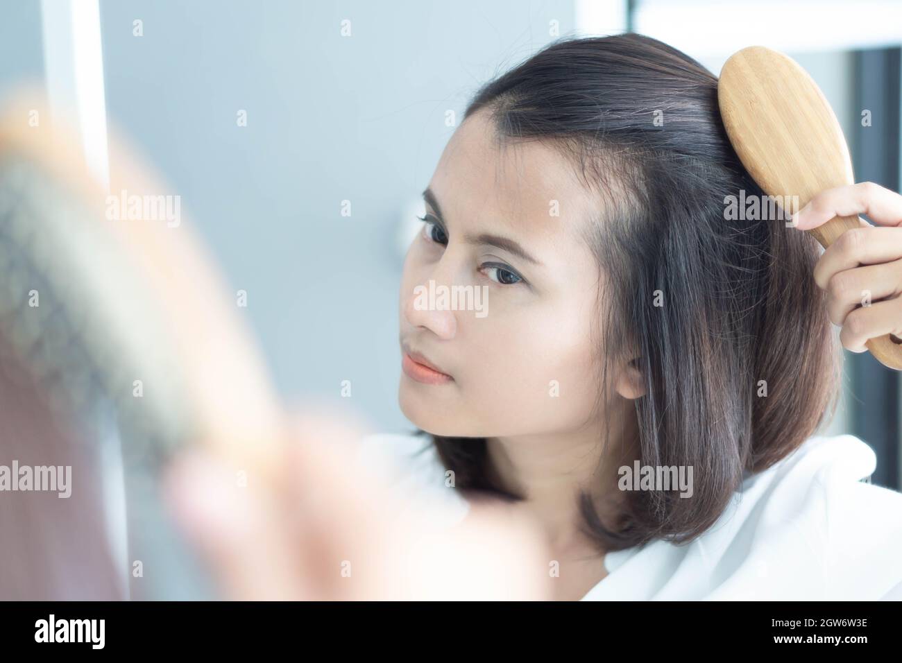 Reflection Of Woman Combing Hair On Mirror Stock Photo