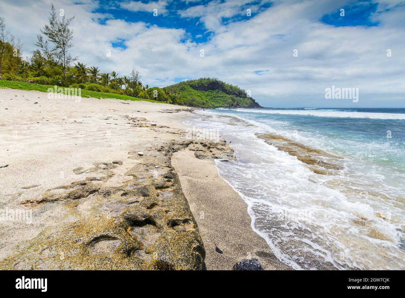 Sunny day with rocks, waves and sand at Grande Anse Beach, Reunion