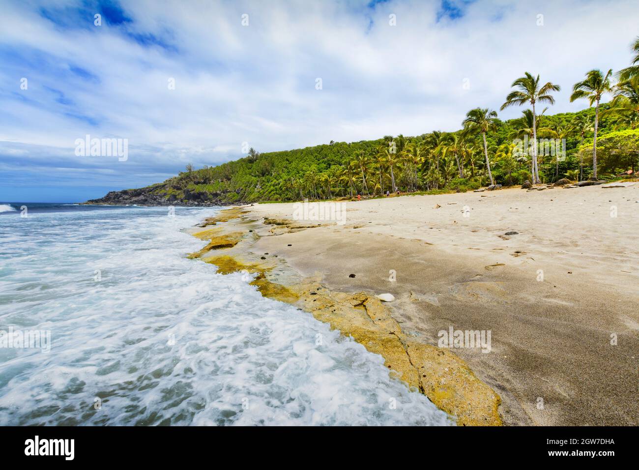 Sunny day with rocks, waves and sand at Grande Anse Beach, Reunion