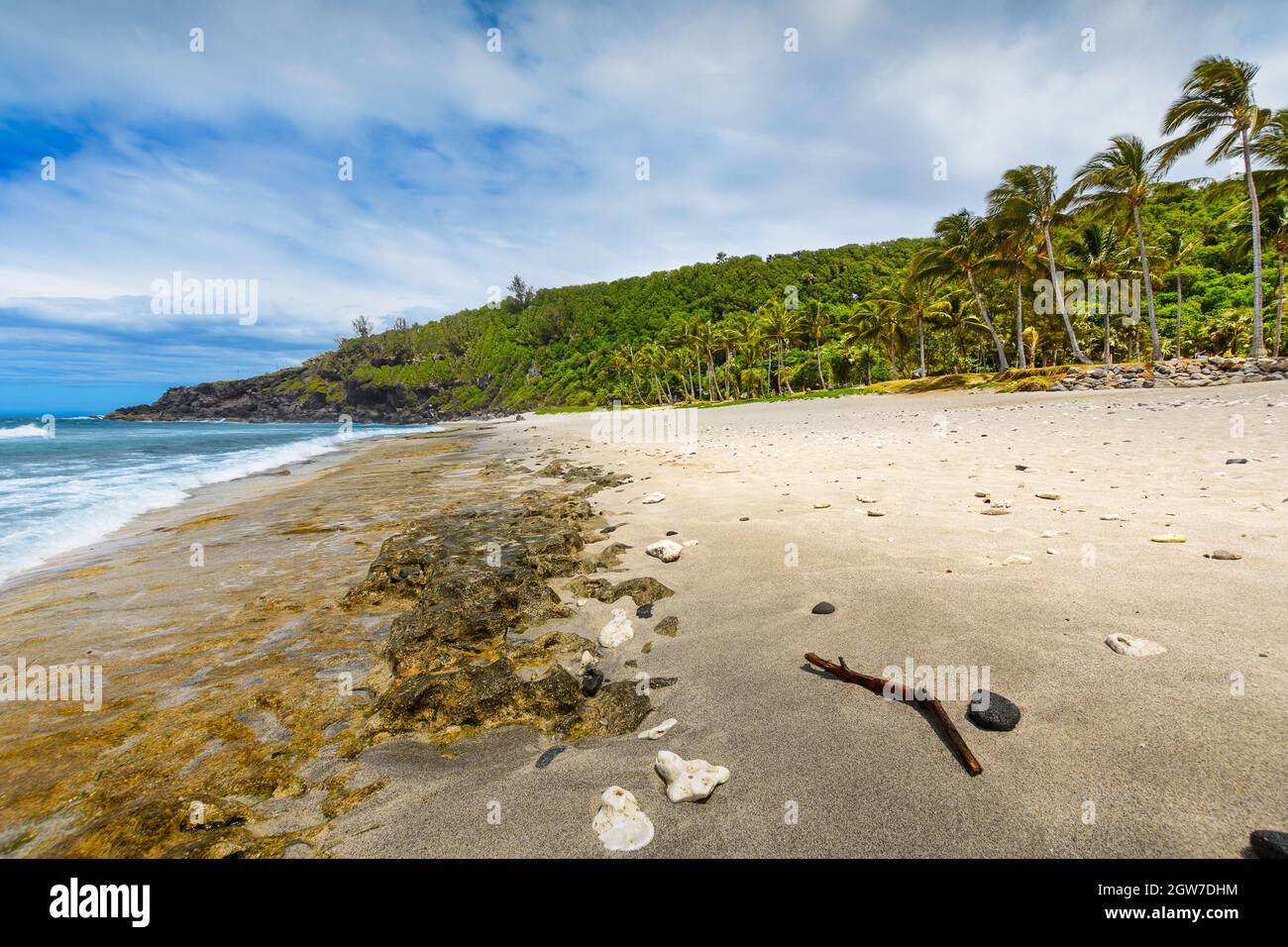 Sunny day with rocks, waves and sand at Grande Anse Beach, Reunion