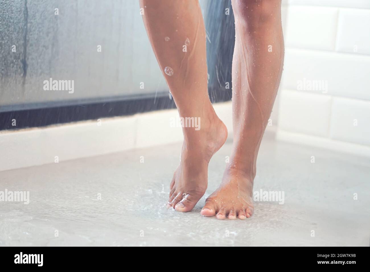 Low Section Of Woman Standing On Wet Floor While Bathing In Bathroom Stock Photo