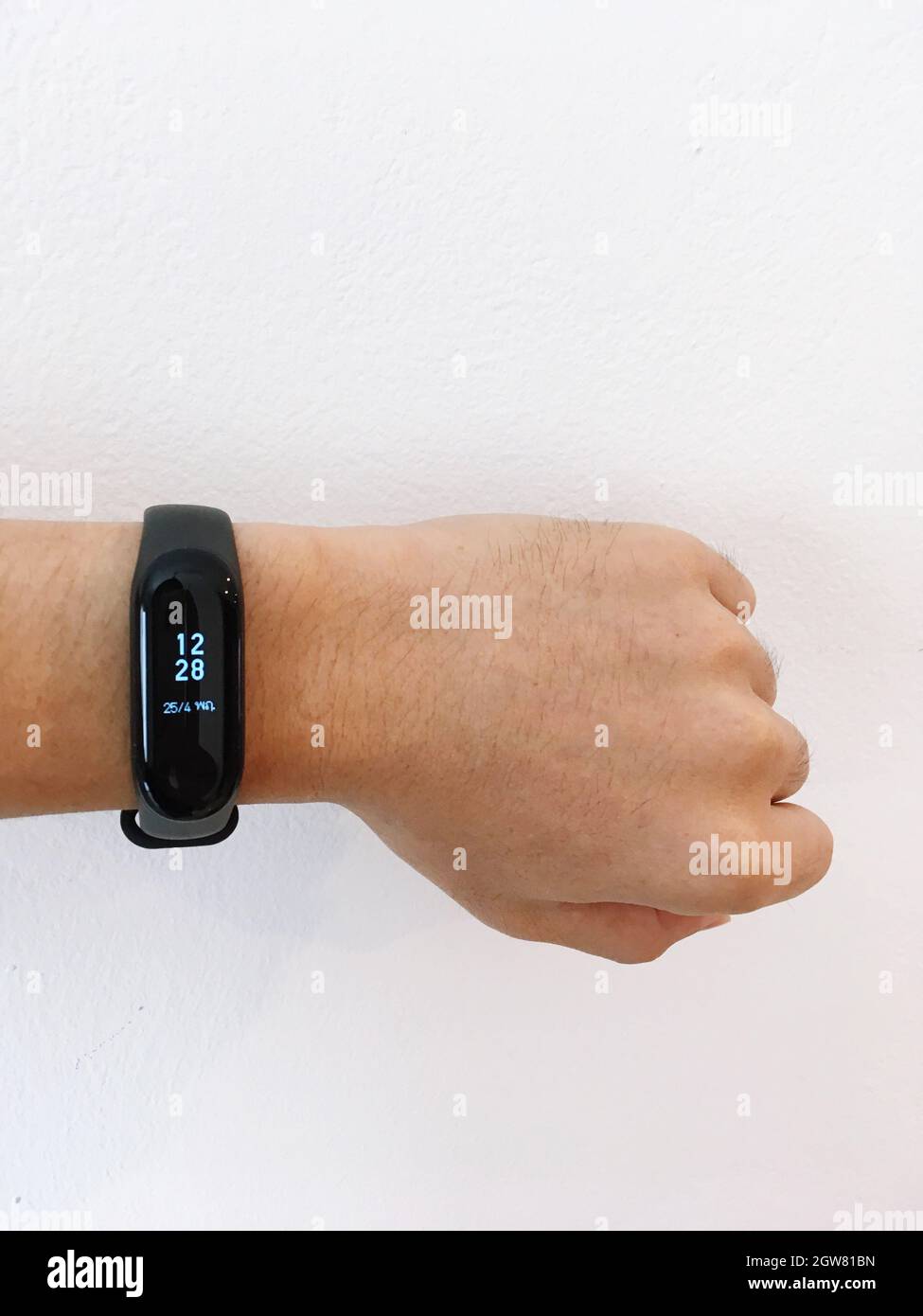 Cropped Hand Wearing Fitness Tracker Against Wall Stock Photo