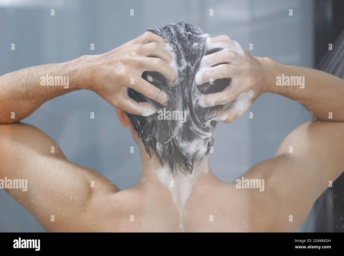 Rear View Of Man Washing Hair While Bathing Stock Photo