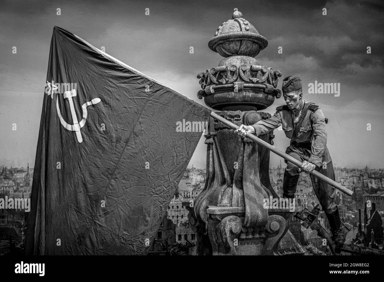 Young Soviet soldier waving a flag in captured Berlin. WWII historical diorama titled 'Memory Speaks. A Way through the War'. Black and white. Stock Photo