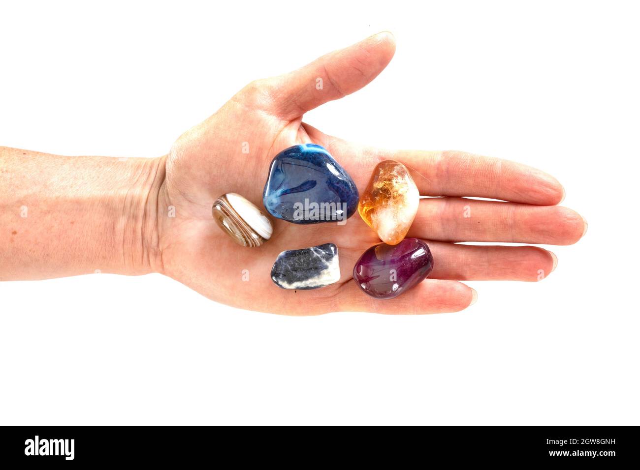 Close-up Of Hand Holding Gemstones Against White Background Stock Photo