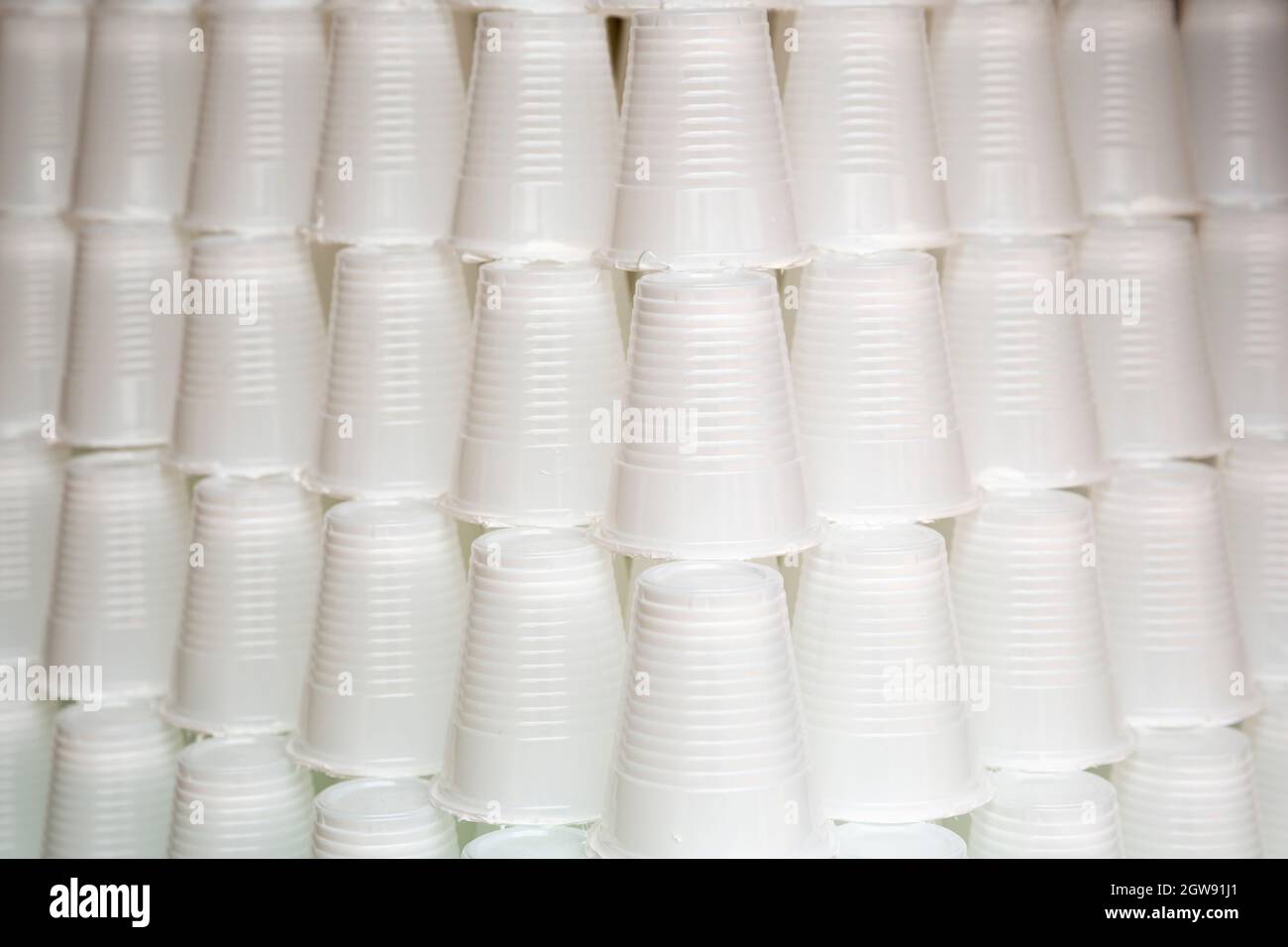 White plastic cups are seen stacked. Most disposable plastic utensils