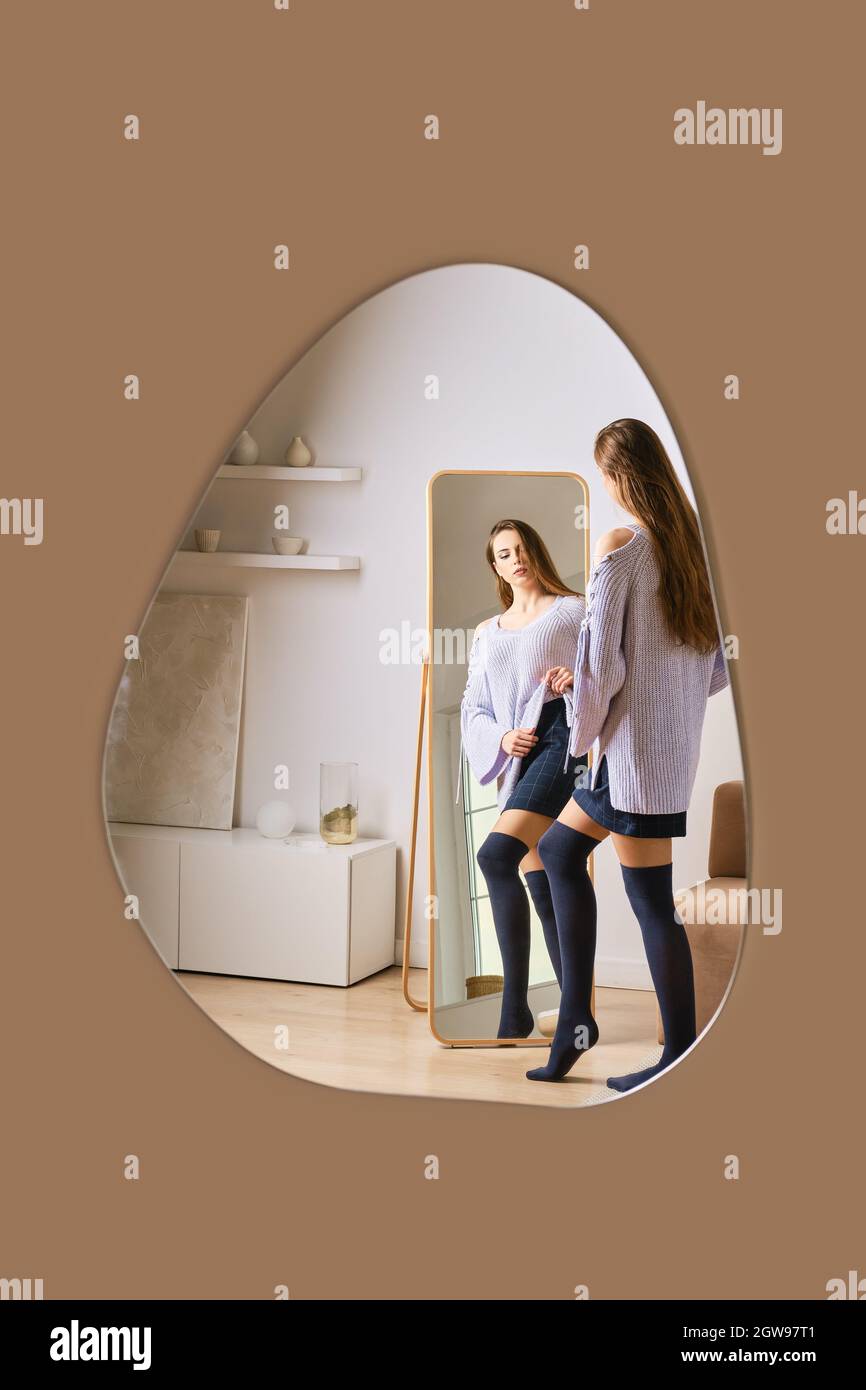 Reflection in mirror of young woman standing in front of the mirror Stock Photo