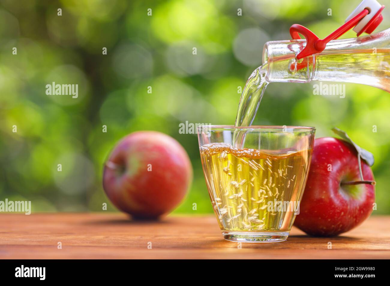 apple cider or juice pouring in glass from bottle Stock Photo Alamy