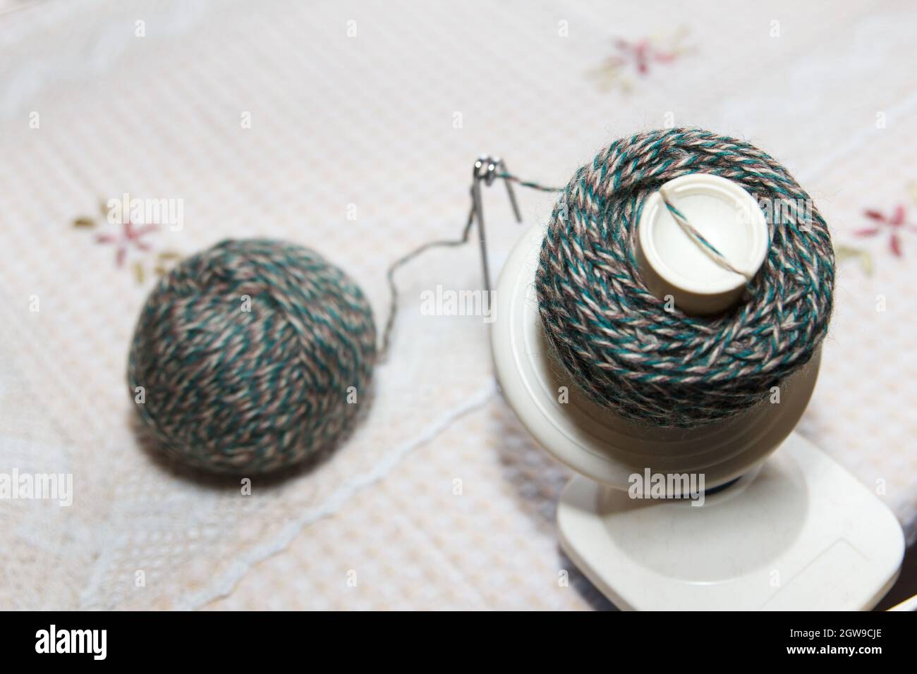 Process of winding wool green yarn from tangle to winding, using a coiler on table Stock Photo