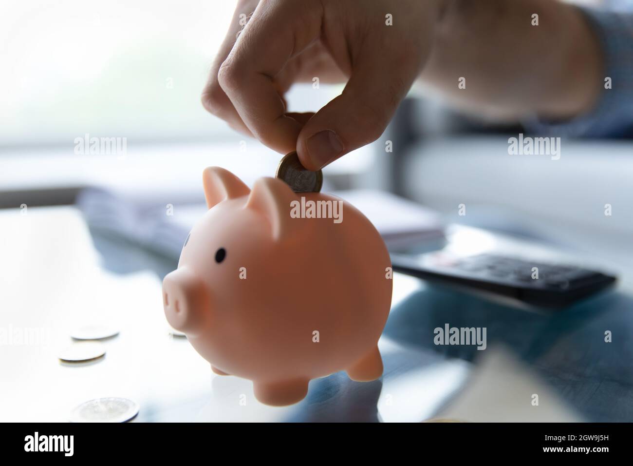Crop close up man putting coin into pink piggy bank Stock Photo - Alamy