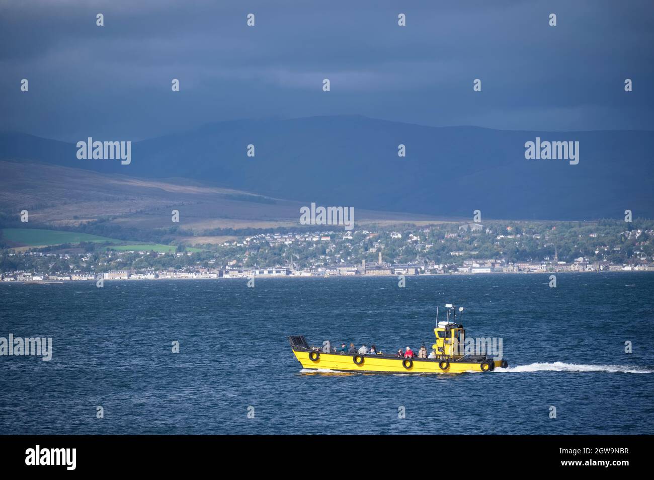 Yellow passenger boat under dark storm clouds in Scotland Stock Photo