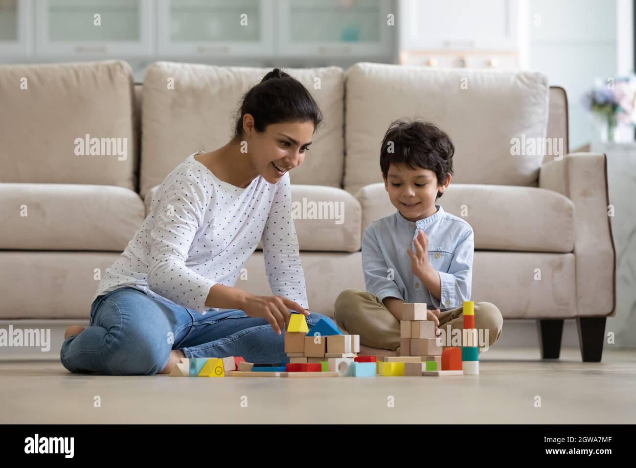Happy young caring indian mother playing toys with small son. Stock Photo