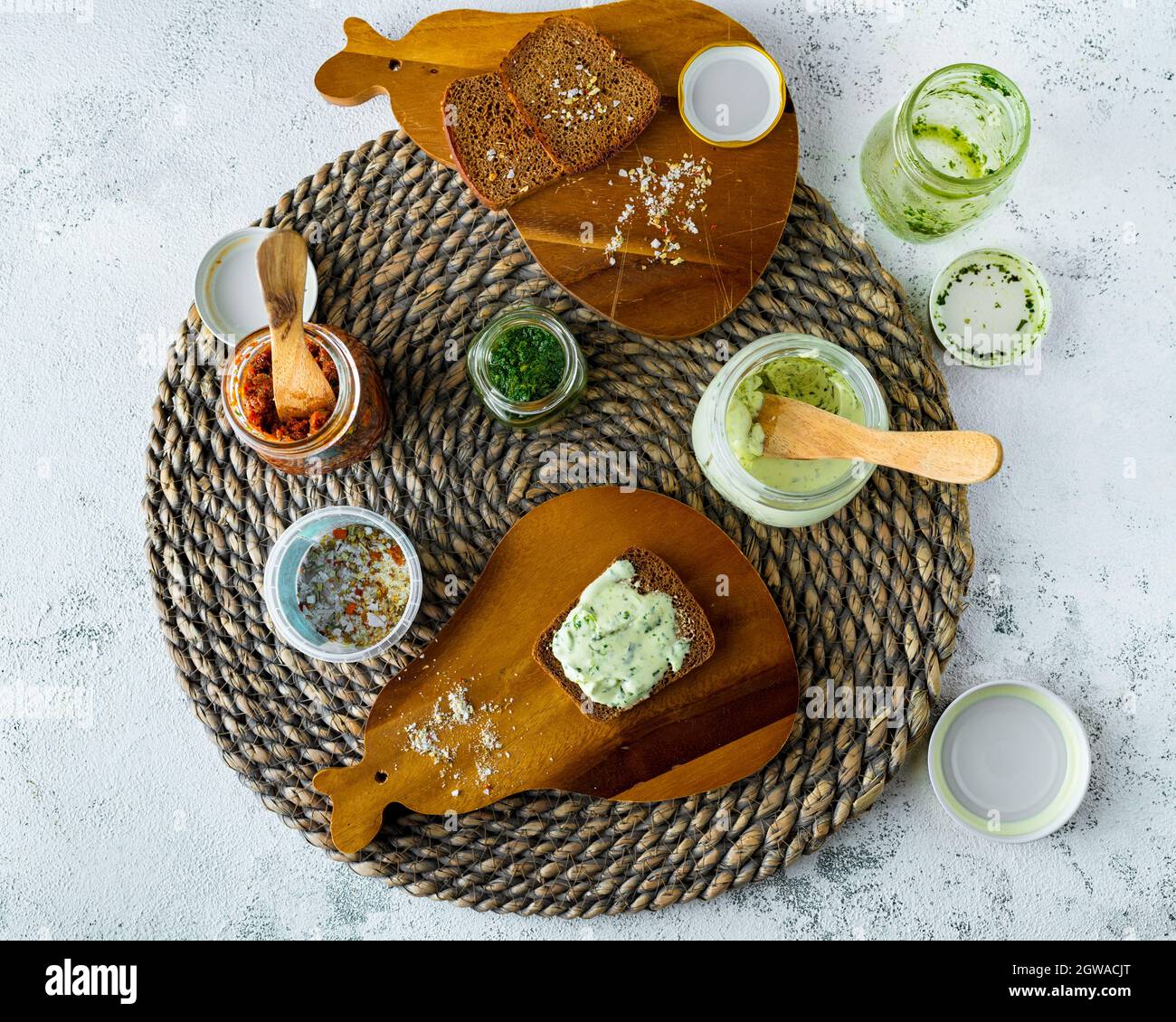 Assorted Plant Based Dips And Spreads On Rattan Placemat And Wooden Boards, Top View Stock Photo