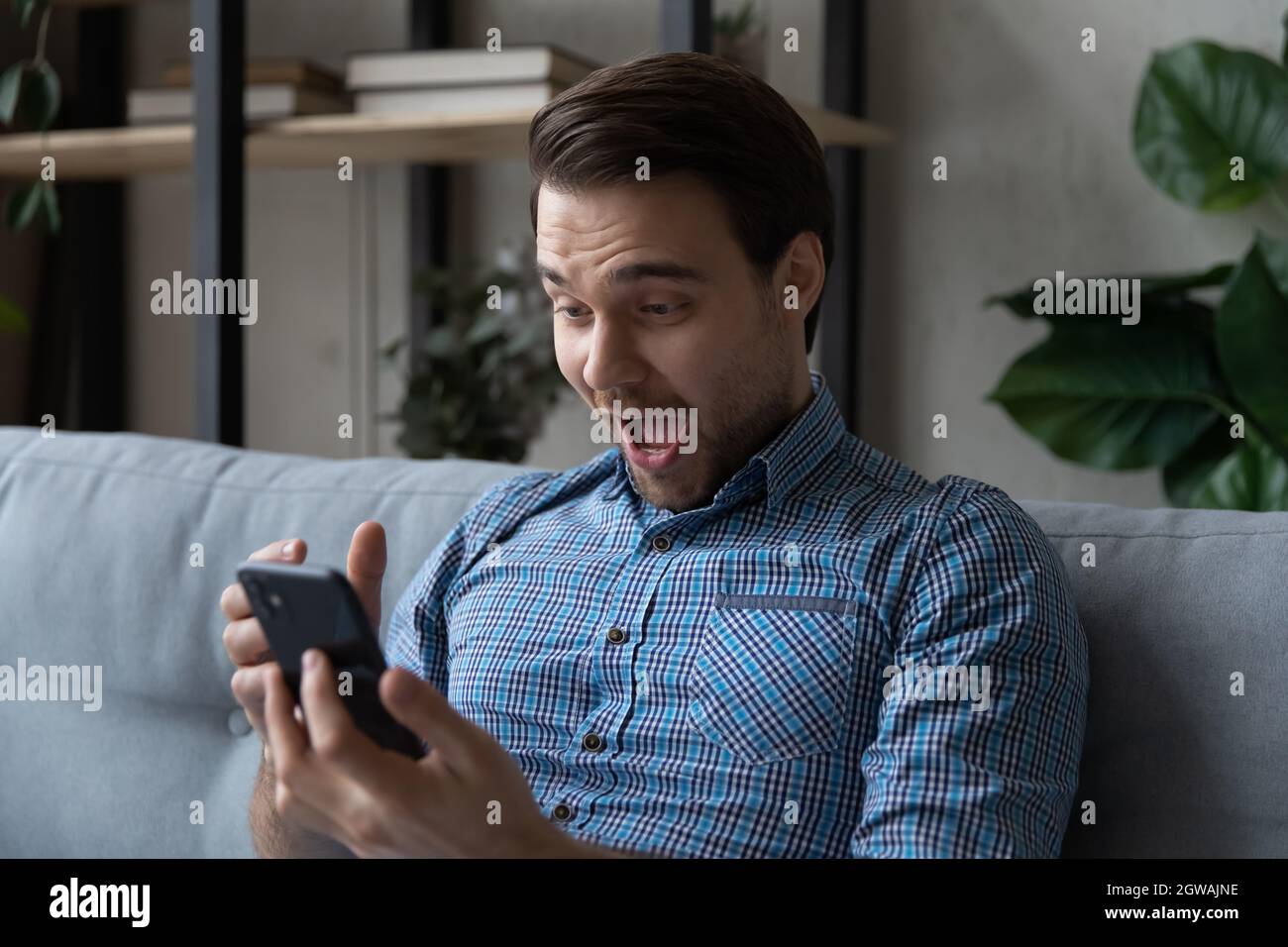 Head shot overjoyed surprised man looking at smartphone screen Stock Photo
