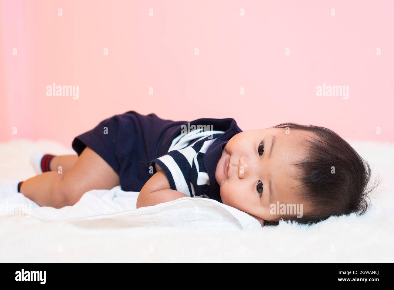 Close-up Of Cute Baby Boy Lying On Bed At Home Stock Photo
