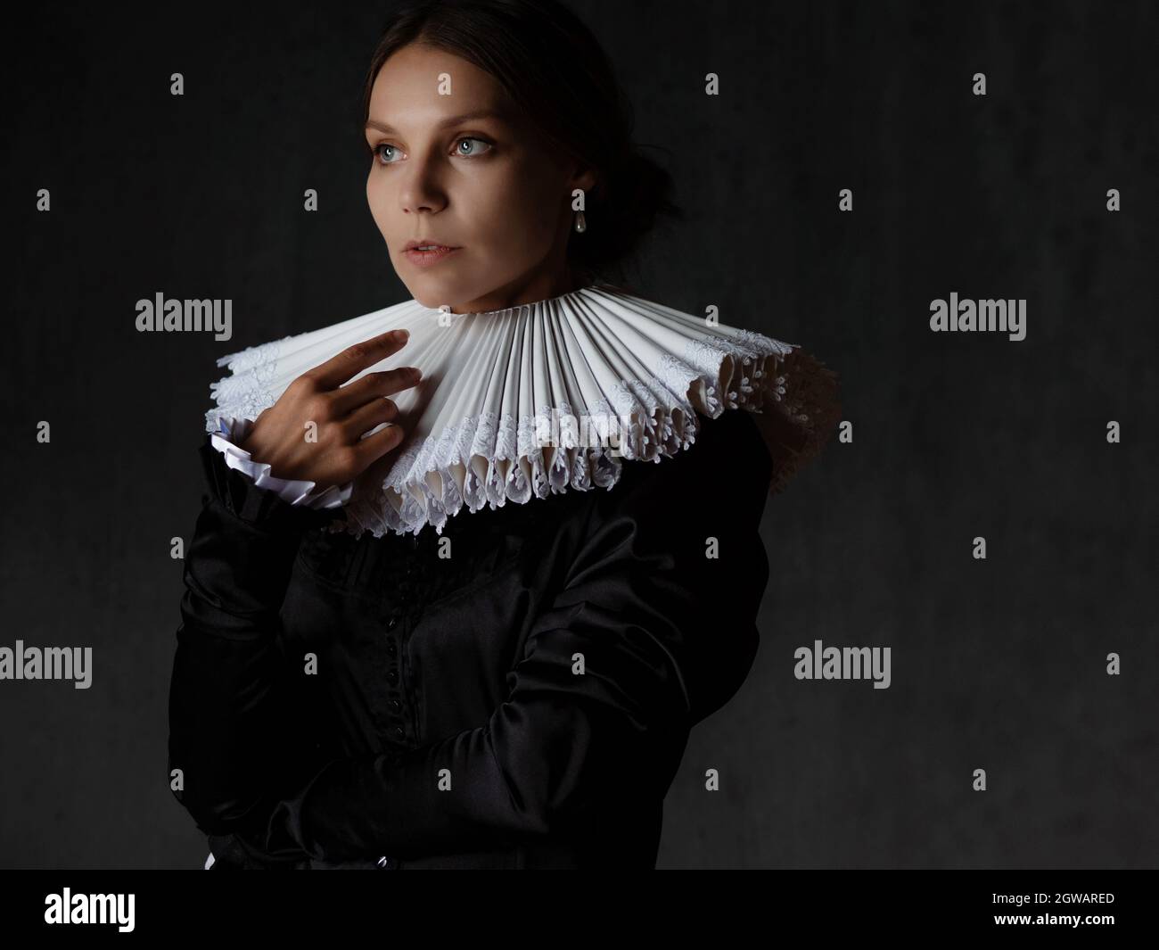 An elegant young lady in an old medieval costume, a portrait in the style of painting. Spanish round collar and dark dress, portrait in the Renaissanc Stock Photo