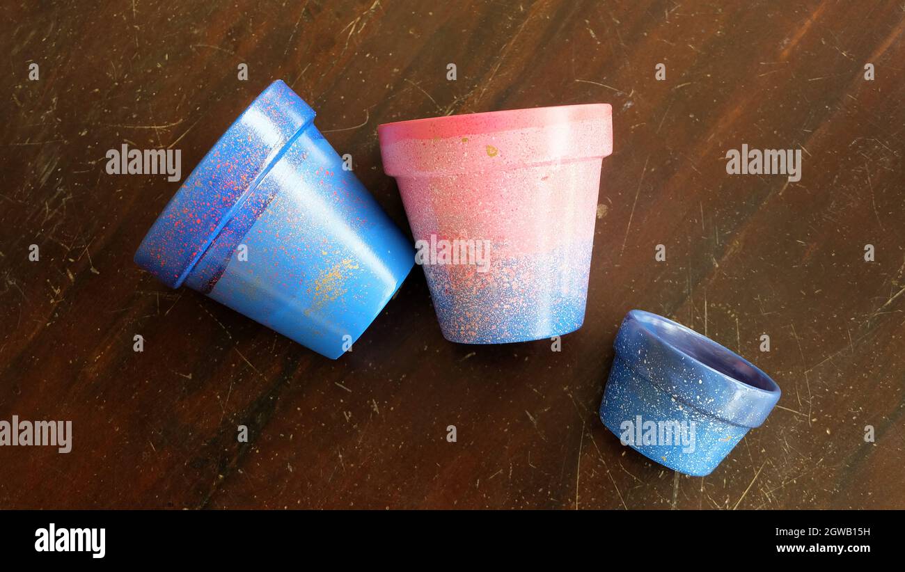 Colorful terracotta pots painted in blue and pink arylic paints. On a wooden surface. Stock Photo