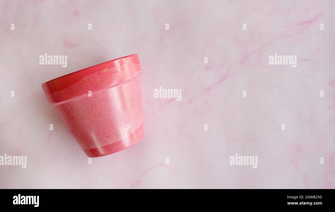 Flat lay of a terracotta pot painted in pink acrylic paint. With copy space on the right and pink background. Stock Photo