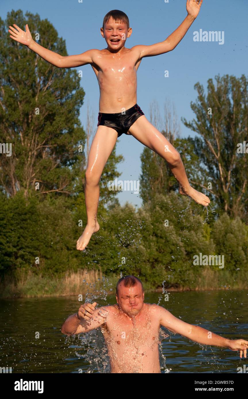 Shirtless Father And Son Enjoying In Water Stock Photo