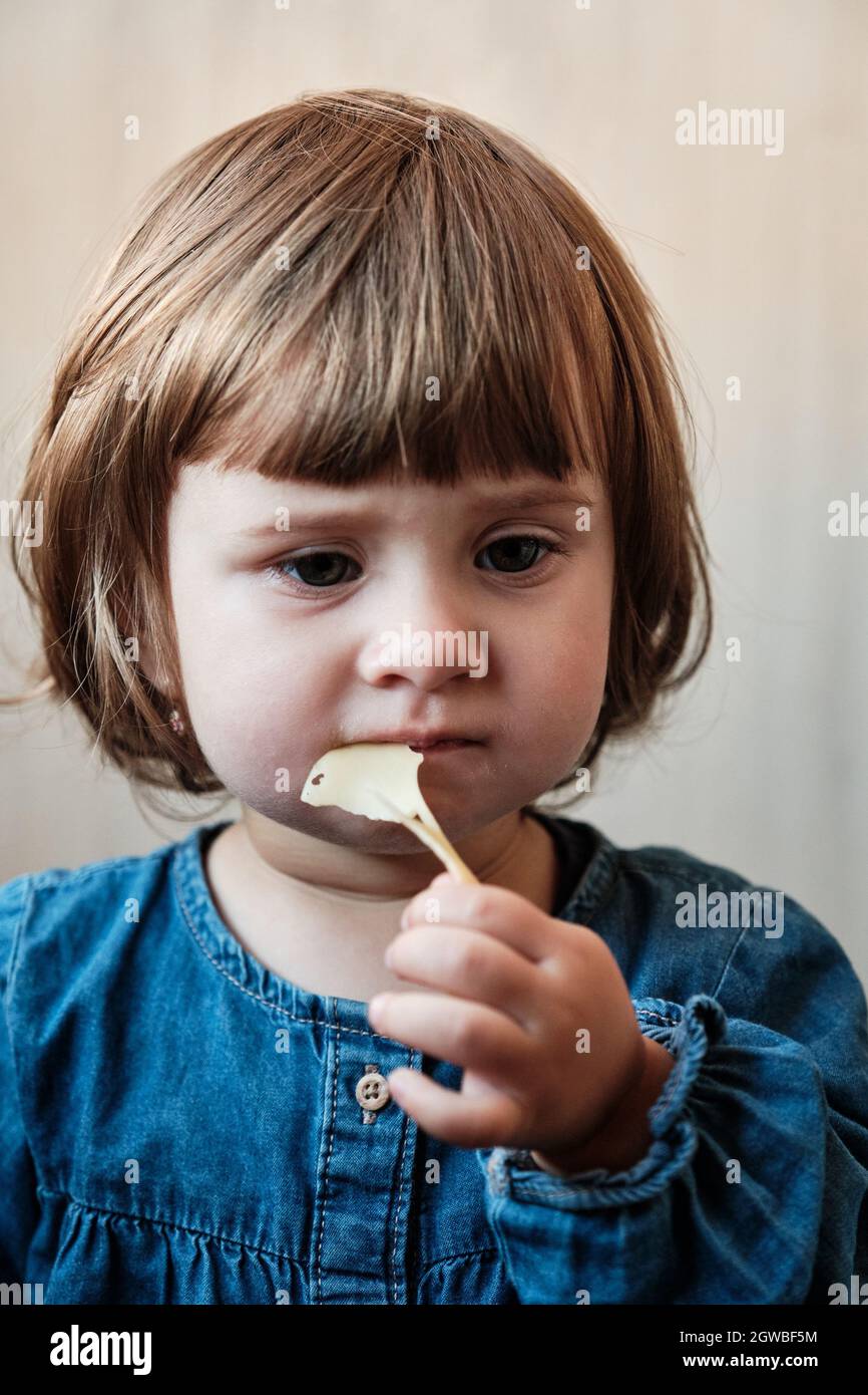 Little baby girl eating cheese. Cute baby enjoy a piece of cheese Stock