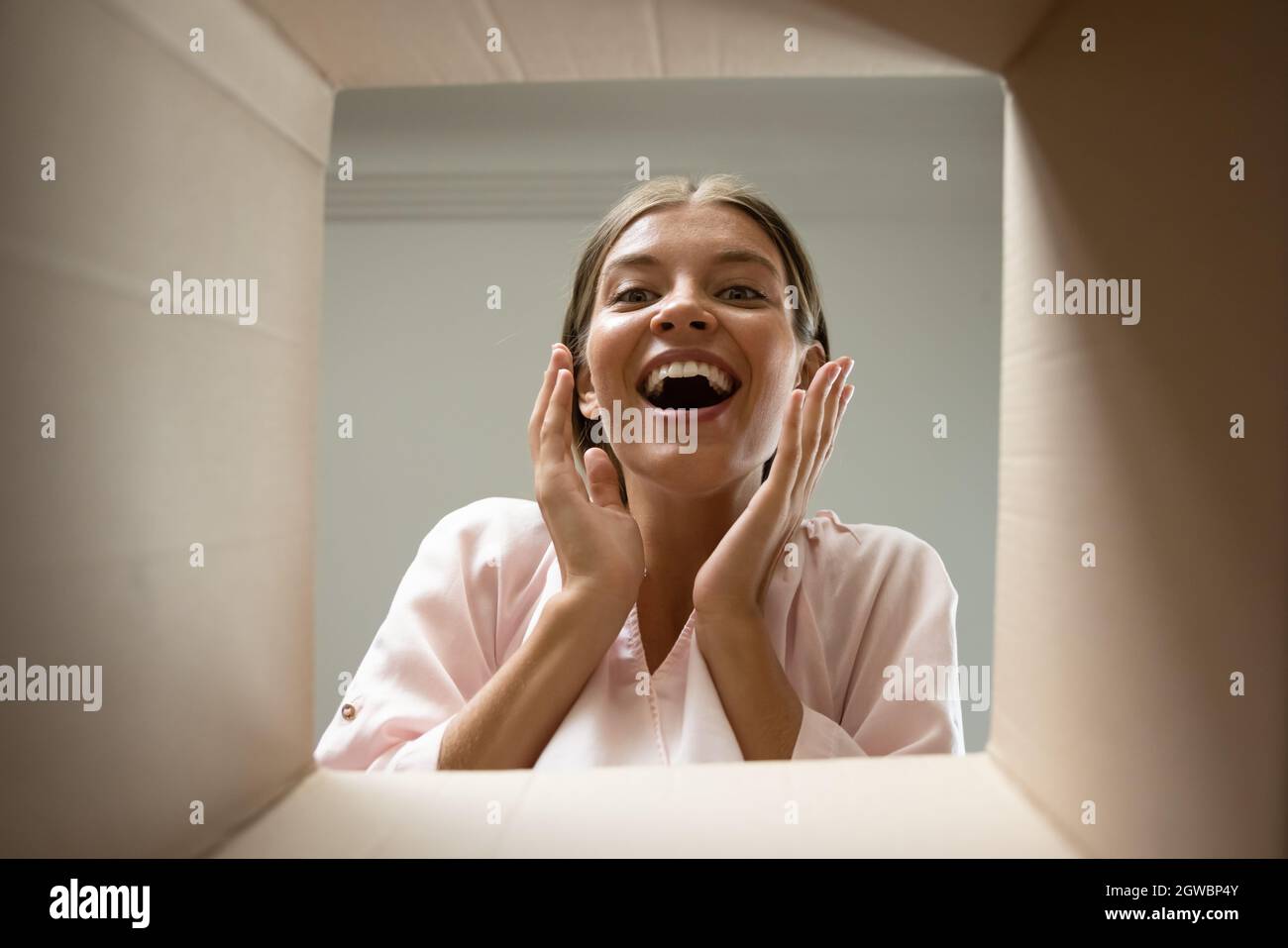 Happy excited customer opening parcel, looking inside package Stock Photo
