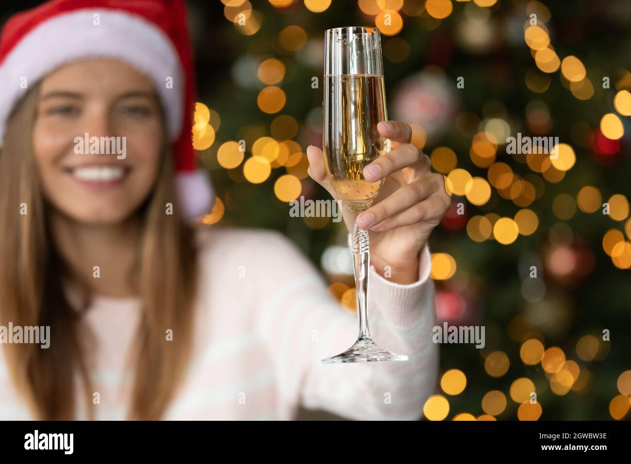 Happy young woman in Santa hat drinking Champagne Stock Photo