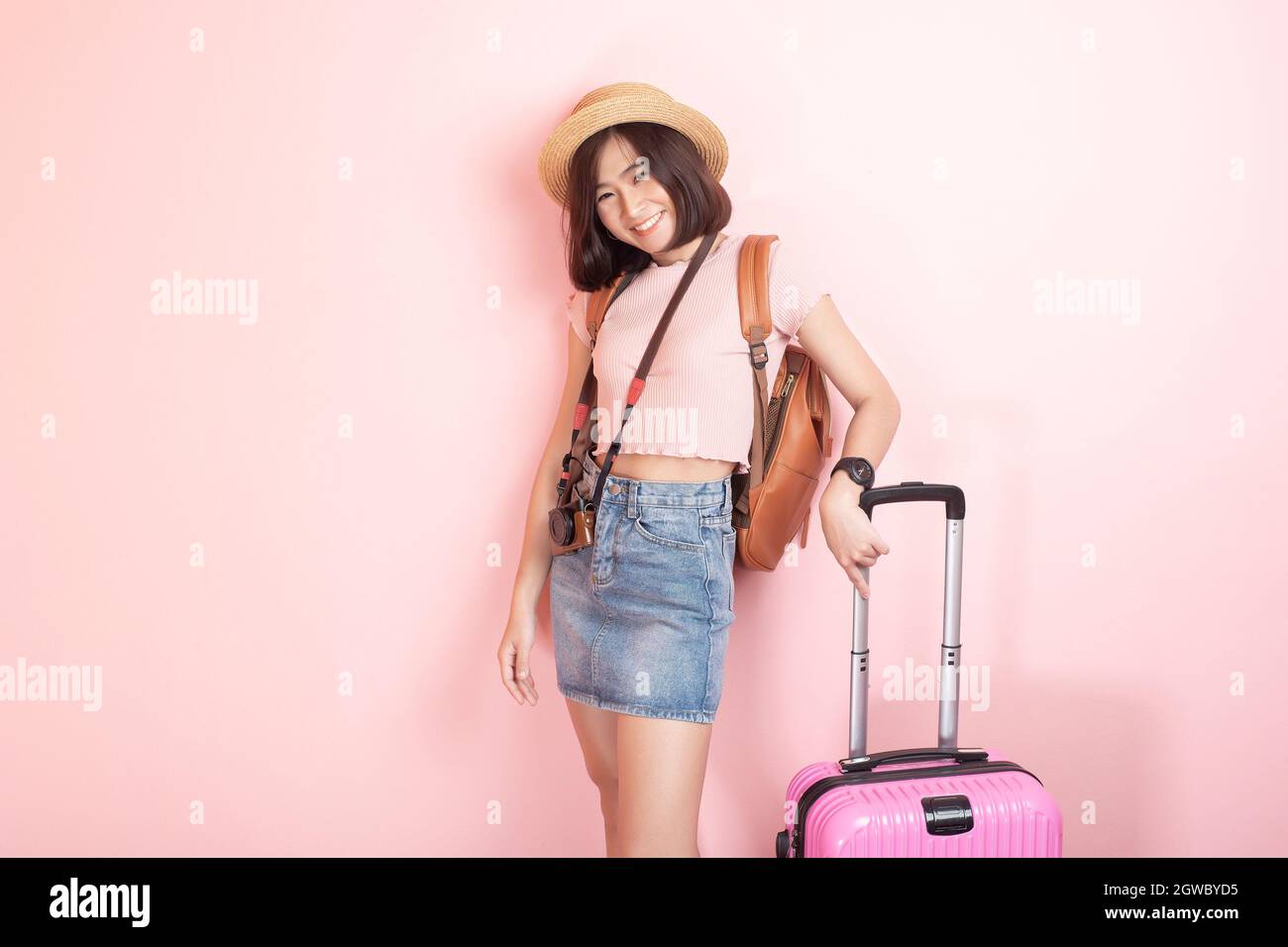 Portrait Of Woman Standing With Suitcase Against Wall Stock Photo