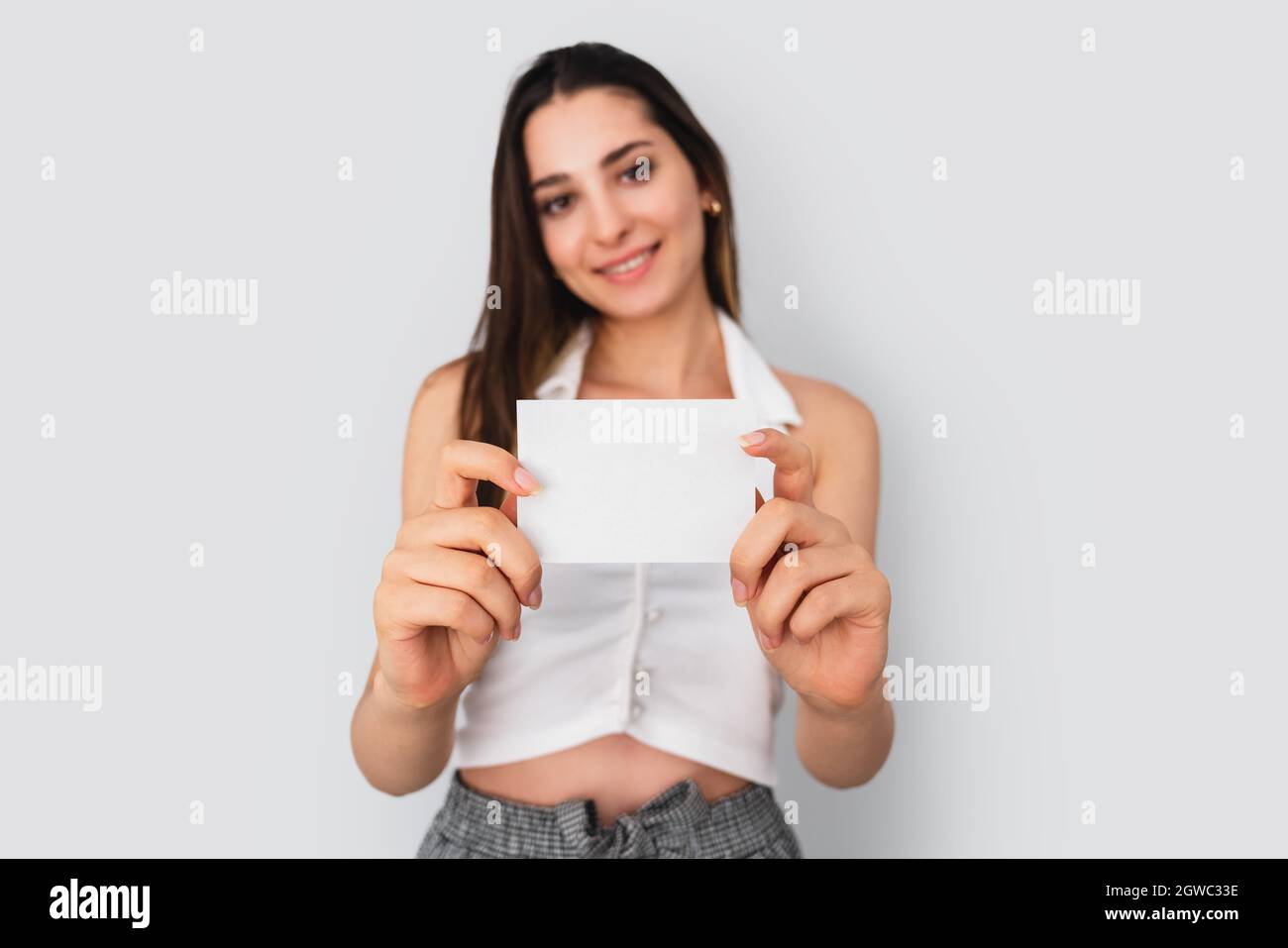 Young brunette woman is holding a blank note paper for mock up use. Silent communication concept. High quality photo Stock Photo