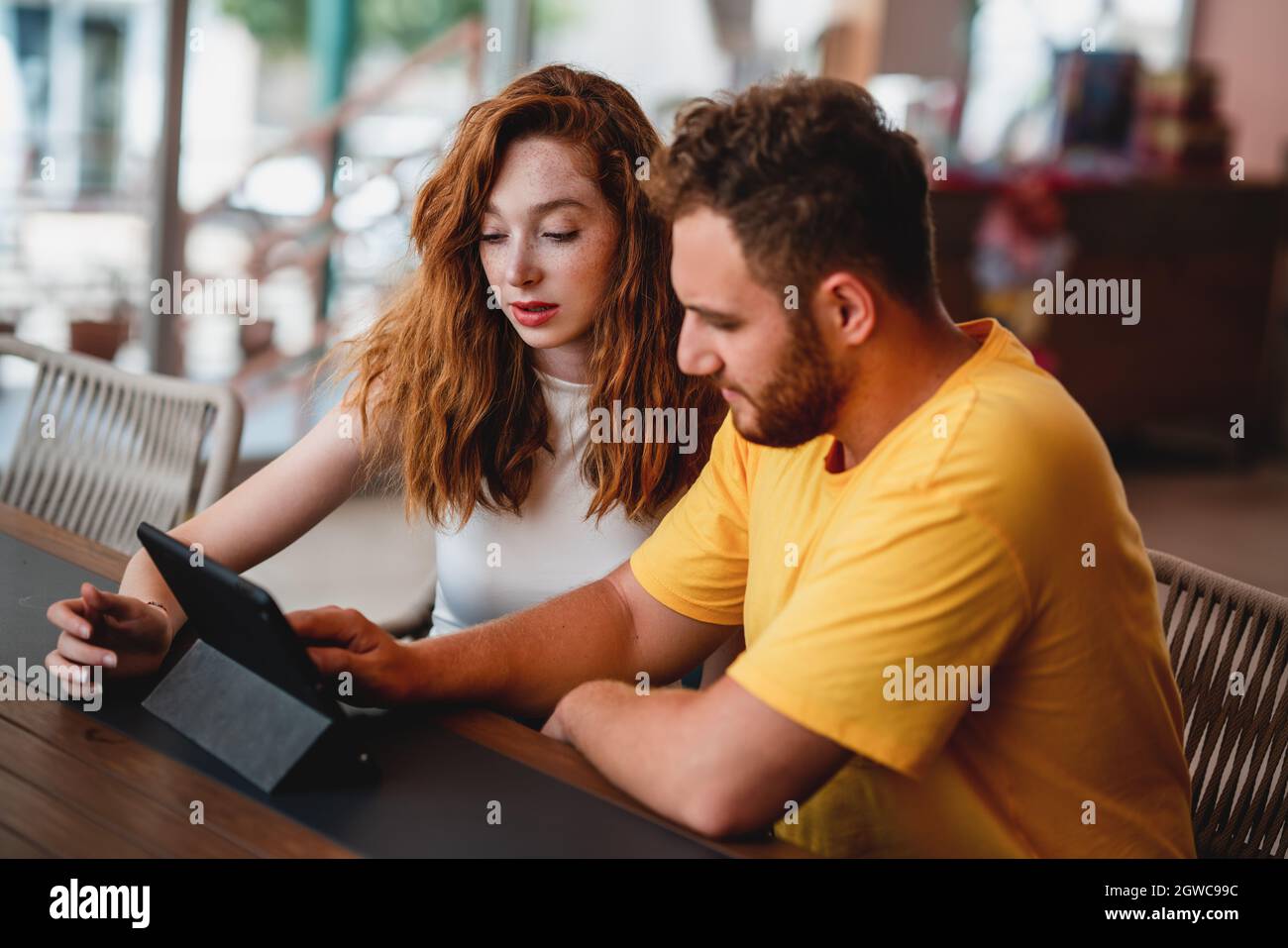 A coung couple friends or colleague sitting in cafe and looking to a tablet. High quality photo Stock Photo