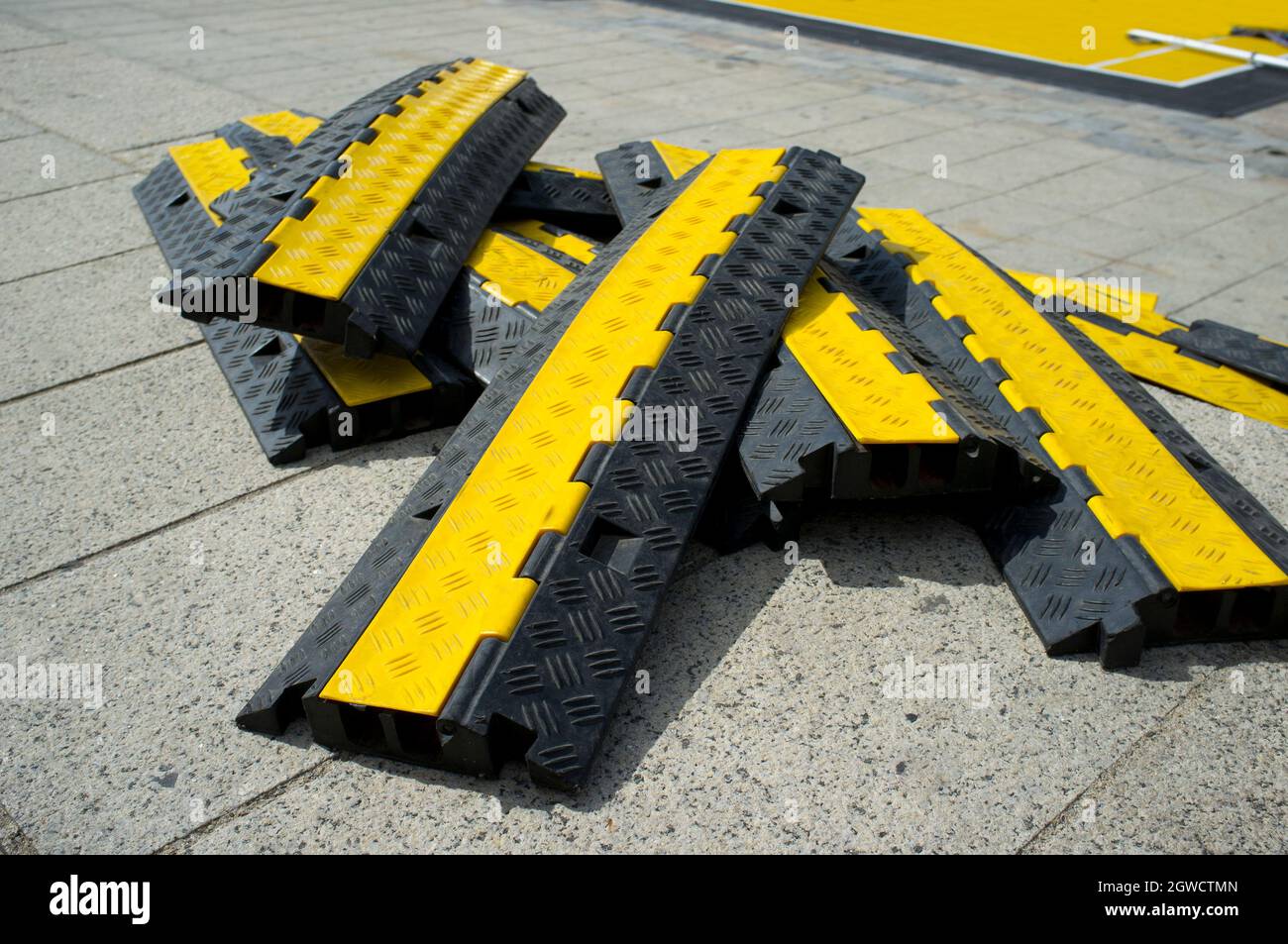 Rubber two channel protector ramp pilled up over urban historic quarter granite floor. Heavy duty cable protectors next to event site Stock Photo