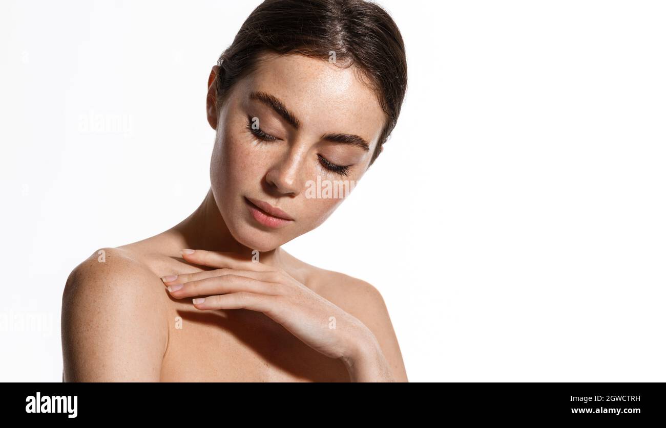 Young woman applying soft skin care cream on her body after shower