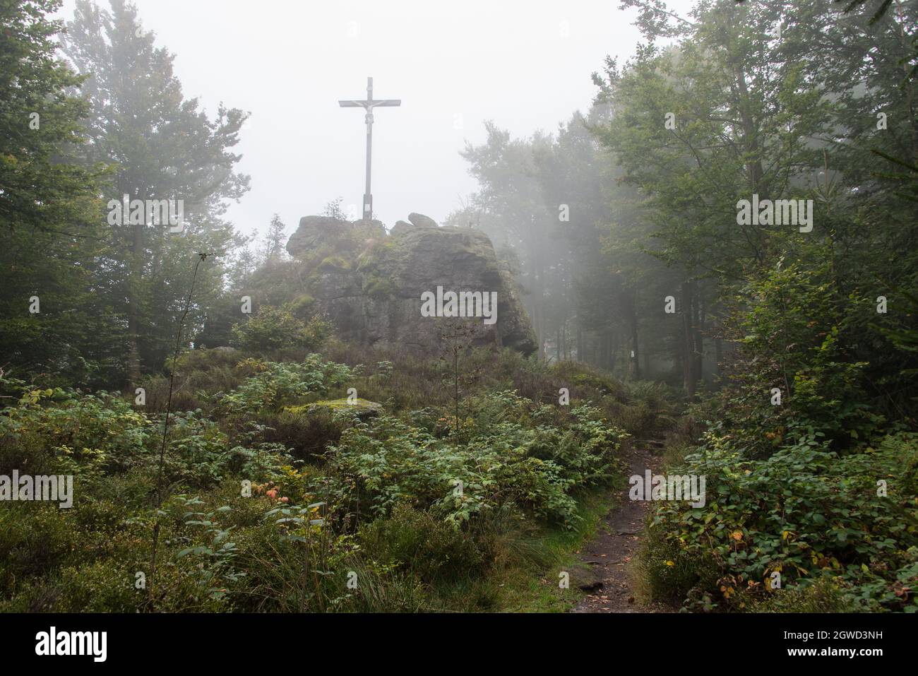 Summit cross at Goldsteig hiking trail in the misty forest of Northern Bavaria. Stock Photo